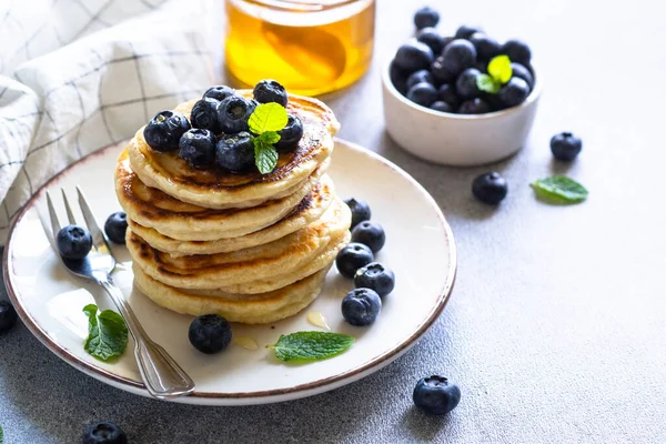 Beyaz taş masada taze yaban mersinli krep ve bal yığını..