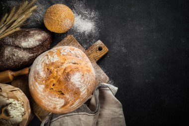 Siyah masada taze ekmek, beyaz çavdar ve çörekler. En üst görüntü.