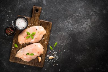 Siyah masada kesme tahtasının üzerinde baharatlı ve otlu tavuk filetosu. Kopyalama alanı olan üst görünüm.