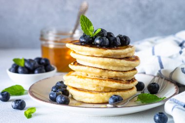Beyaz masada taze yaban mersinli krep ve bal..