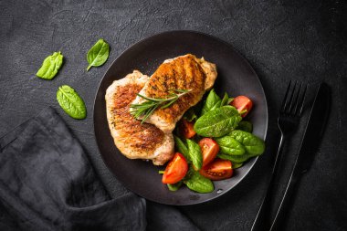 Izgara et. Taze salatalı domuz bifteği. Siyah masadaki en üst görüntü. Keto diyet öğle yemeği.