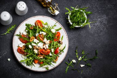 Domatesli, mavi peynirli ve cevizli Arugula salatası. Sağlıklı vejetaryen yemeği. En üst görüntü.