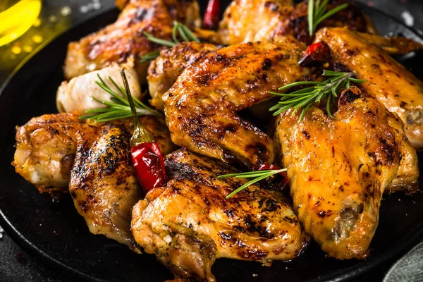 Siyah tabakta baharatlı ızgara tavuk kanadı. Kapat.