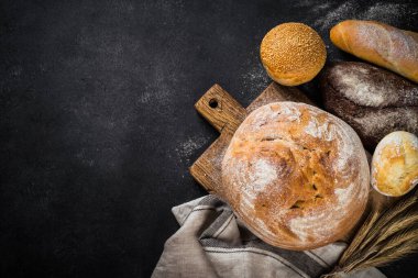 Siyah masada taze ekmek, beyaz çavdar ve çörekler. En üst görüntü.