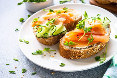 Krem peynirli, somonlu ve salatalıklı sandviç. Sağlıklı kahvaltı ya da atıştırmalık. Kopyalama alanı olan üst görünüm.