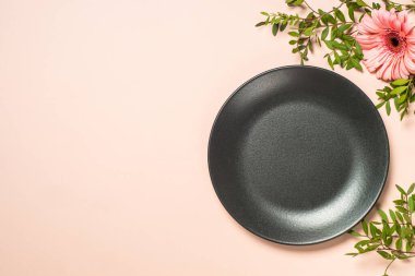 Siyah plakalı masa ayarları ve pembe arka planda çiçekler. Kopyalama alanı olan üst görünüm.