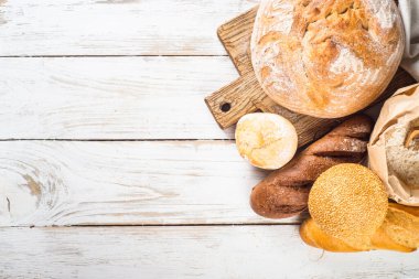 Beyaz mutfak masasında taze ekmek ve çörekler..