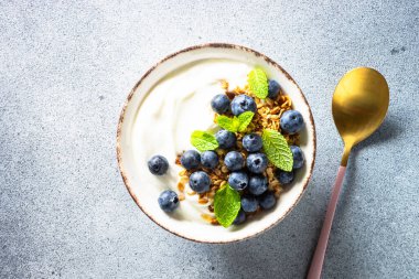 Tahıllı yoğurt ve hafif taş masada taze yaban mersini. Sağlıklı kahvaltı. Üst görünüm.