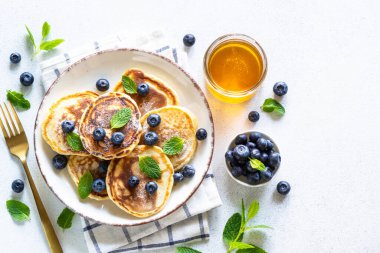 Beyaz masada taze yaban mersinli krep ve bal. Kopyalama alanı olan üst görünüm.