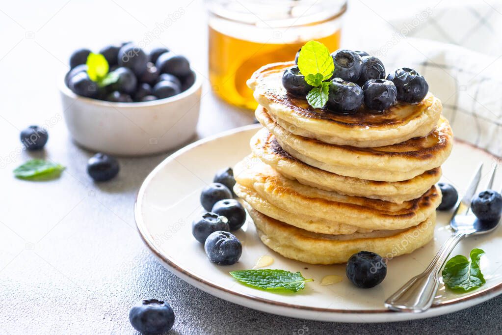 Pancakes stack with fresh blueberries and honey close up.