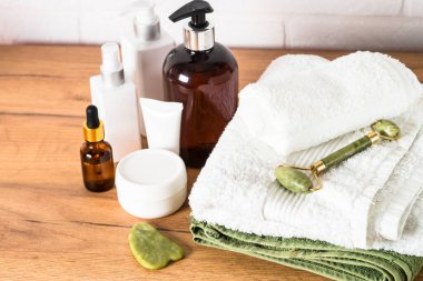 Beyaz banyodaki spa ürünleri. Bir şişe sabun, kozmetik ürünleri ve beyaz banyoda yığınla havlu..