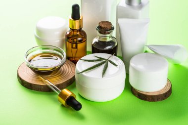 Yeşil arka planda esrar kozmetik ürünleri. Doğal kozmetik konsepti. Krema, sabun, serum, temel yağ ve diğerleri..