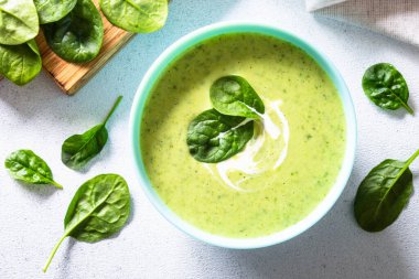 Beyaz masada yeşil ıspanak kremalı çorba. Sağlıklı vejetaryen yemeği. Üst görünüm .