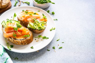 Krem peynirli, somonlu ve salatalıklı sandviç. Sağlıklı kahvaltı ya da atıştırmalık. Kopyalama alanı olan üst görünüm.