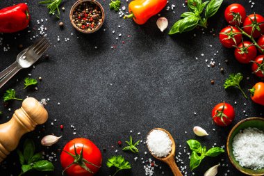 Yemek çerçevesi. Yemek pişirme arka planı siyah taş masada. Taze sebzeler, otlar ve baharatlar. Kopyalama alanı olan üst görünüm.