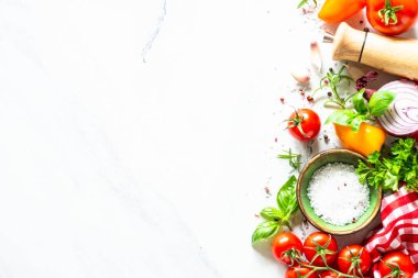 Yemek arkaplanı beyaz masada. Taze sebzeler, otlar ve baharatlar. Kopyalama alanı olan üst görünüm.