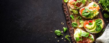 Krem peynir, prosciutto, somon, avokado, taze yeşillik ve sebzeli sandviç seti. Uzun pankart biçimi.