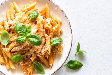 Domates soslu makarna, fesleğen ve parmesanlı beyaz masa. Domates soslu makarna alla arrabbiata. Kopyalama alanı olan üst görünüm.