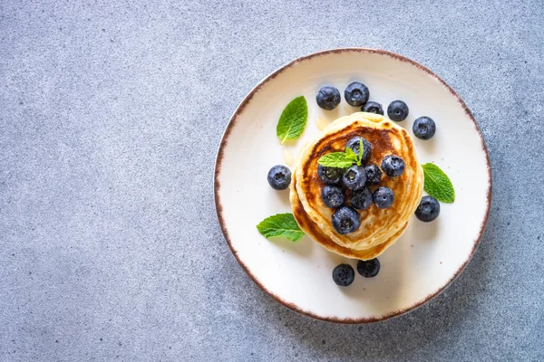 パンケーキは石のテーブルに新鮮なブルーベリーと蜂蜜で積み上げます 健康的な朝食やデザート コピースペース付きのトップビュー — ストック写真