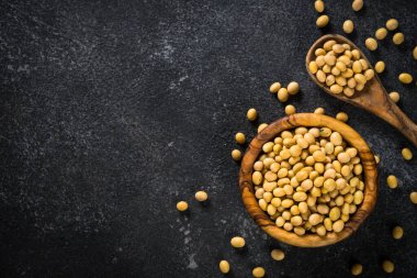 Soya bitkisel protein kaynağıdır. Vejetaryen yemeği. Siyah taş masadaki tahta kasede soya fasulyesi..