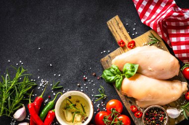 Baharatlı tavuk fileto göğsü ve siyah tahta masada sebzeler. Üst görünüm.