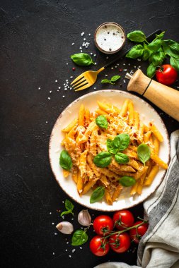 Arka planda domates soslu makarna, fesleğen ve parmesan. Üst görüntü dikey.