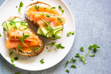 Krem peynirli, somonlu ve salatalıklı sandviç. Sağlıklı kahvaltı ya da atıştırmalık. Kopyalama alanı olan üst görünüm.