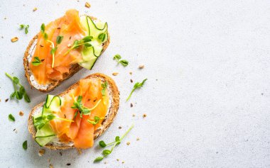 Krem peynirli sandviç, beyaz taş masada salatalık ve somon. Kopyalama alanı olan üst görünüm.