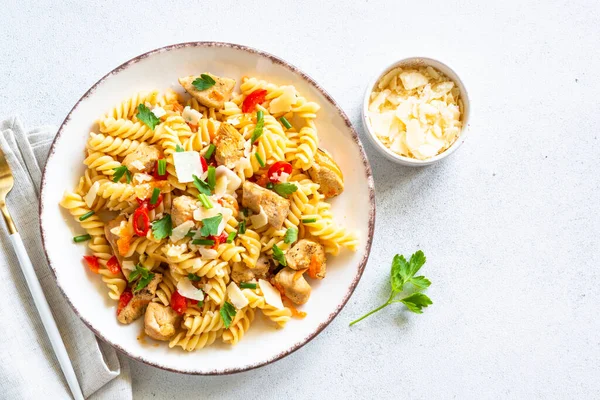 Pasta with turkey meat, vegetables and parmesan on white. Top view with copy space.