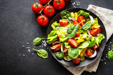 Siyah tabak içinde taze salata. Vejetaryen yemeği. Kopyalama alanı olan üst görünüm.