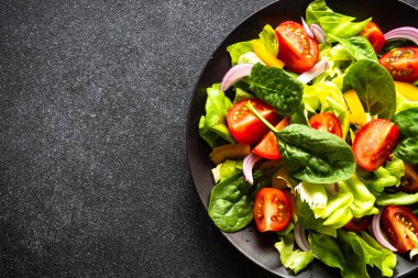 Siyah tabak içinde taze salata. Vejetaryen yemeği. Kopyalama alanı olan üst görünüm.