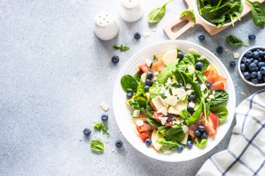 Ispanaklı, roka, jamon, armut, yabanmersini ve parmesanlı sağlıklı salata. Beyaz arkaplanda üst görünüm.