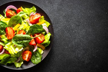 Siyah tabak içinde taze salata. Vejetaryen yemeği. Kopyalama alanı olan üst görünüm.