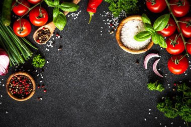 Yemek arkaplanı siyah taş masa. Taze sebzeler, otlar ve baharatlar. Fotokopi alanı ile pişirme malzemeleri.
