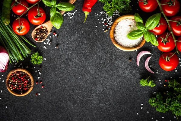 Yemek arkaplanı siyah taş masa. Taze sebzeler, otlar ve baharatlar. Fotokopi alanı ile pişirme malzemeleri.