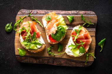 Krem peynirli sandviç seti, prosciutto, somon, avokado ve taze yeşillik. En üstteki görünüm koyu.
