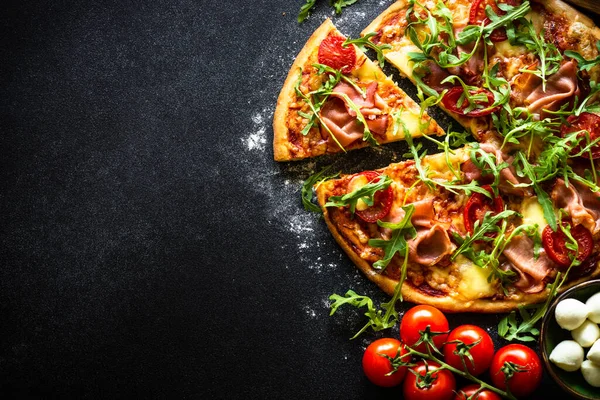 比萨的黑色背景 意大利传统披萨加火腿 西红柿和牛油果 平面上有文字的空间 — 图库照片