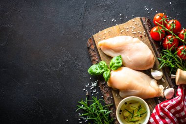 Baharatlı tavuk filetosu ve sebzeler siyah taş masada tahta kesme tahtasında. Kopyalama alanı olan üst görünüm.