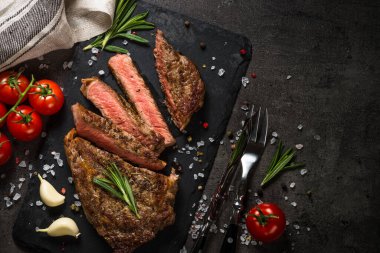 Siyah üzerine biftek. Izgara biftek striploin orta pişmiş, servis tahtasında. Kopyalama alanı olan üst görünüm.