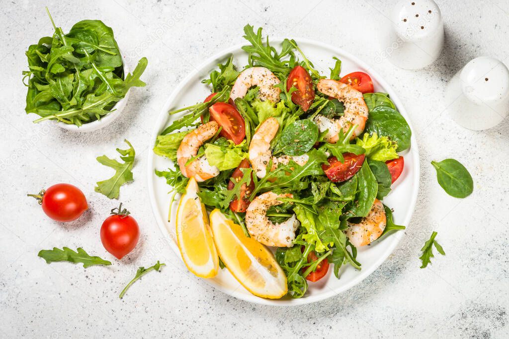 Shrimp salad with vegetables and leaves. Top view on white table.