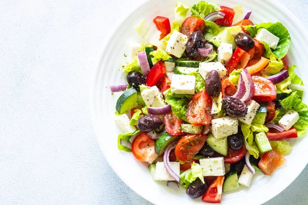 Greek salad. Vegetable salad with tomato, cucumber, feta cheese, greek olives and olive oil. Top view, close up.