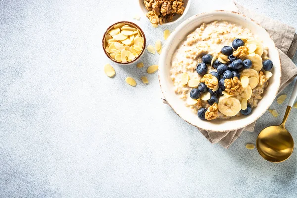 Beyaz arka planda fındıklı yulaf ezmesi ve böğürtlen kabı. Kopyalama alanı olan üst görünüm.
