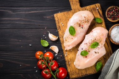Tavuk fileto, taze et, otlar ve baharatlar koyu ahşap masada. Kopyalama alanı olan en üst görüntü.