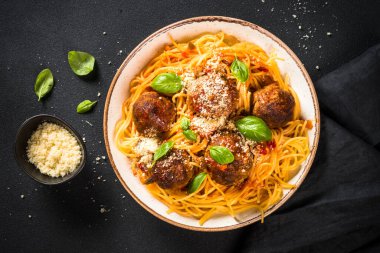 Köfte ve domates soslu makarna. Koyu taş masada. Geleneksel İtalyan yemeği. Kopyalama alanı olan üst görünüm.