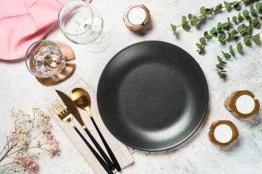 Tabaklı masa, yeşil yapraklar ve beyaz mutfak masasında çatal bıçak takımı. Üst görünüm.