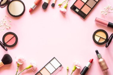 Makeup professional cosmetics on pink background with flowers. Flat lay with copy space.