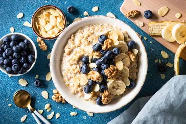 Mavi arka planda böğürtlenli ve fındıklı yulaf ezmesi. Üst görünüm.