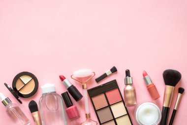 Makeup professional cosmetics on pink background. Cream, lipstick, shadow and brushes. Flat lay image with copy space.