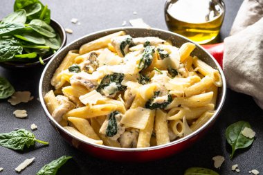 Pasta penne with chicken and spinach in creamy sauce in the skillet.