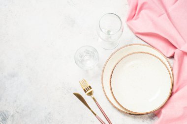 Tabaklı masa, çiçekler ve çatal bıçak takımı beyaz mutfak masasında. Bahar ya da yaz sofrası. Kopyalama alanı olan üst görünüm.